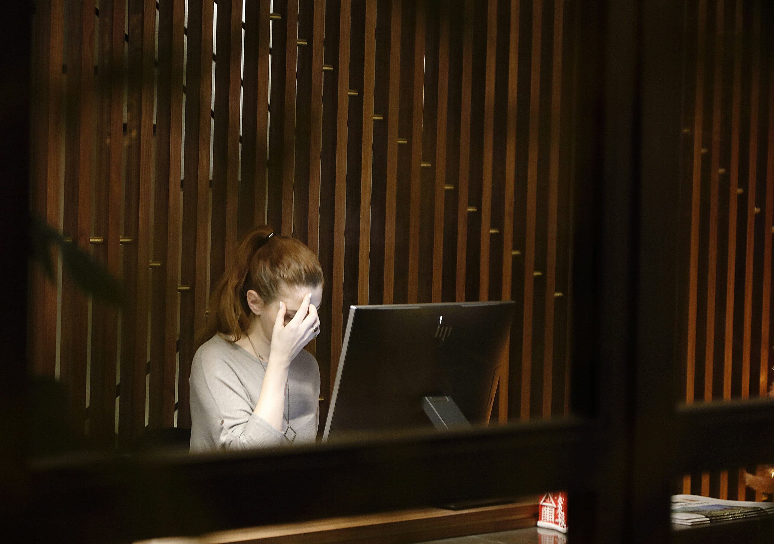 Une femme, assise devant son ordinateur, tard le soir, se prends la tête dans les mains. Elle est épuisée, au bord du burn out.